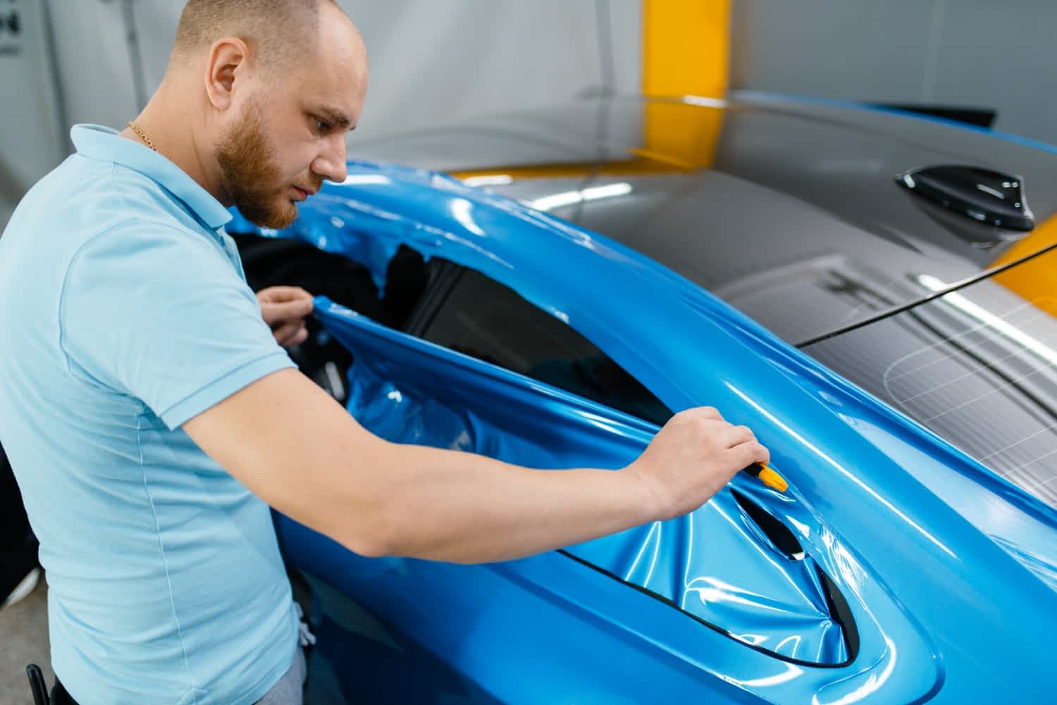 specjalista nakłada folię na auto